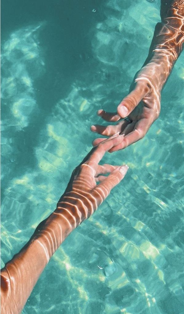 Hands meeting over clear ocean water